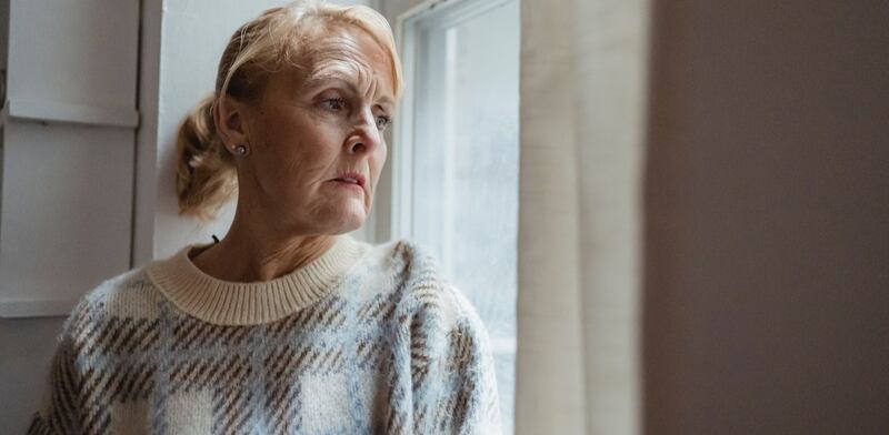 Donna triste che guarda dalla finestra