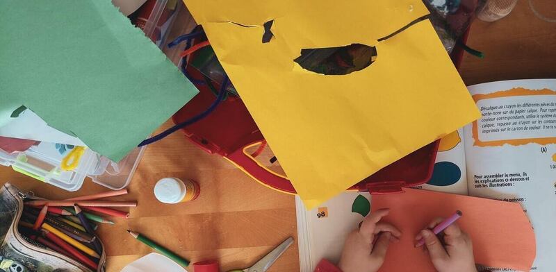 Bambina che disegna maschere con il cartoncino