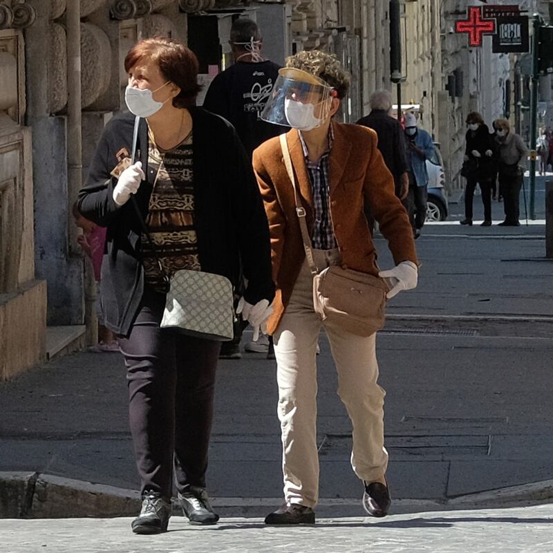 Due signore attraversano la strada con i dispositivi di protezione (Foto LaPresse)