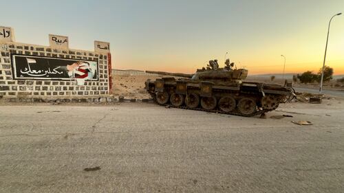 Carro armato abbandonato davanti a un murales pro Assad