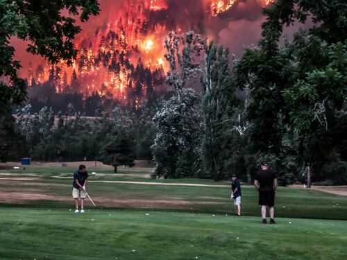 Giocano a golf durante l'incendio: metafora del cambiamento climatico
