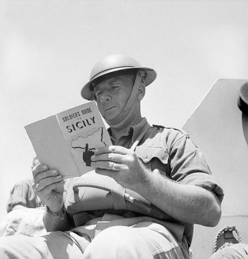 Un soldato britannico mentre legge una guida sulla Sicilia per i soldati nel luglio 1943.
