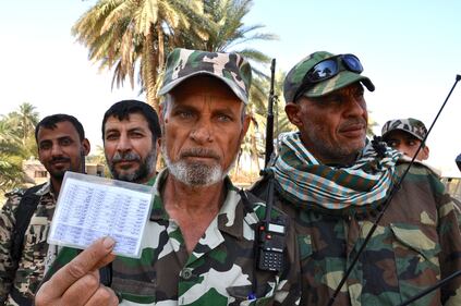 Un ufficiale sciita mostra la lista dei nomi dei combattenti del Califfato torvata fra le macerie della battaglia di Jurf al Shakar. Alcuni nomi sono sauditi e altri afghani