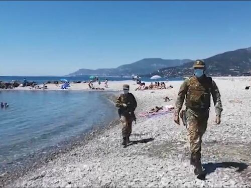 Militari con mitra e anfibi in spiaggia a Ventimiglia: "Controllano le distanze di sicurezza e i migranti la fanno da padroni"