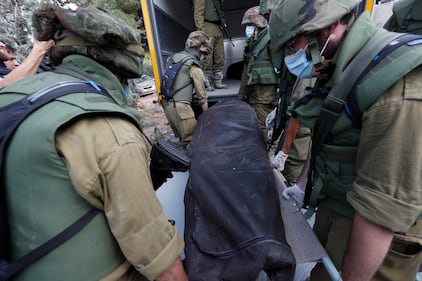 I soldati israeliani radunano e portano via i cadaveri dal kibbutz 8