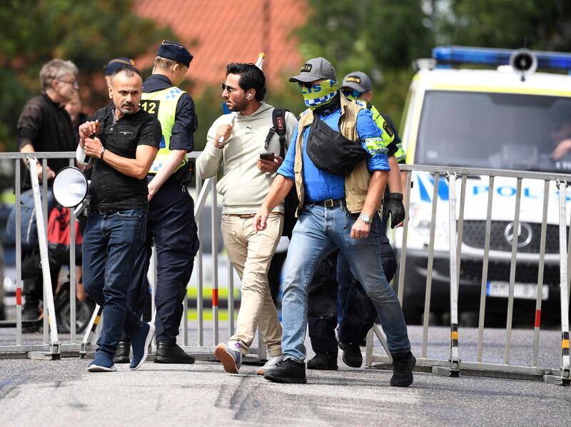Salwan Momika scortato dalla polizia fuori dall'ambasciata irachena a Stoccolma.