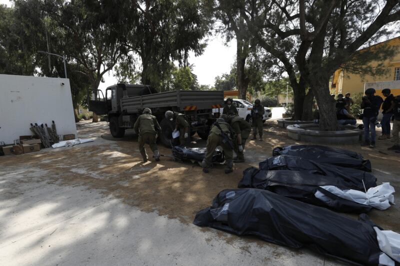 I soldati israeliani radunano e portano via i cadaveri dal kibbutz 7