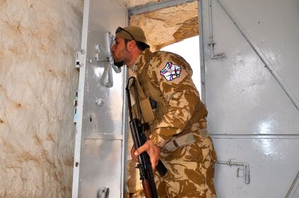 Volontario cristiano bacia la croce all'ingresso della chiesa di San Giorgio nel villaggio abbandonato di Bakufa a nord di Mosul